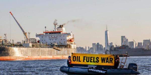 Un barco con un cartel que enuncia en ingles 'el petroleo alimenta la guerra'