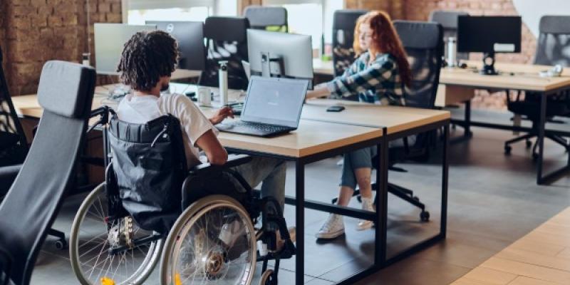 Un joven en silla de ruedas en una oficina | Foto de 123rf/dotshok