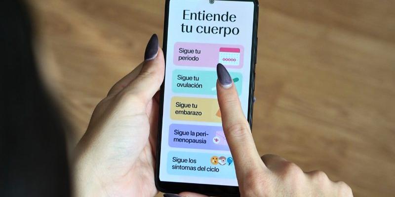 Dedo de una mujer en la pantalla de un móvil utilizando una app menstrual