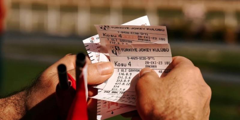 Manos de una persona con boletos de una apuesta deportiva