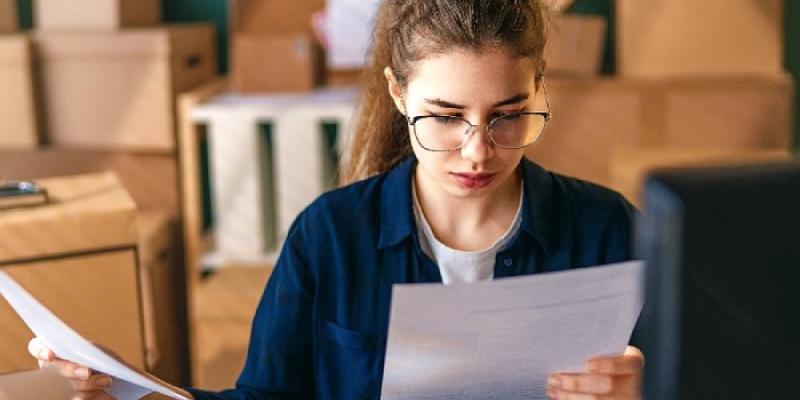 Una mujer analiza unos documentos delante de un ordenador