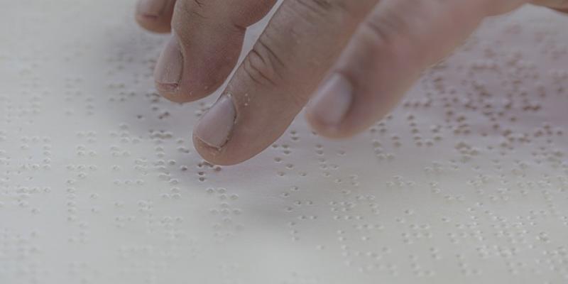 Dedos de una persona leyendo en braille