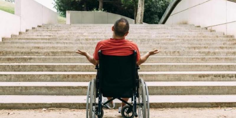 Hombre en silla de ruedas indignado frente a las escaleras. 