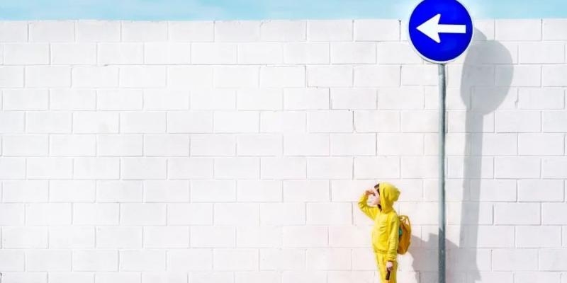 Niña vestida de amarillo frente a una señal azul luchando contra las barreras cognitivas