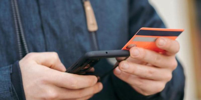 Manos de una persona con su tarjeta de crédito y teléfono móvil