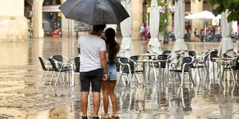 Una pareja refugiada en un paraguas en una tormenta de verano