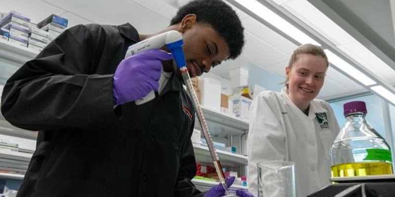 Leon Johnson, estudiante de primer año de neurociencia, y Alice McQueney, estudiante de posgrado de segundo año, pipetean dicromato de potasio para un experimento