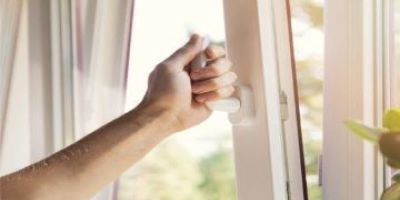 Una mano abre una ventana para ventilar la sala 
