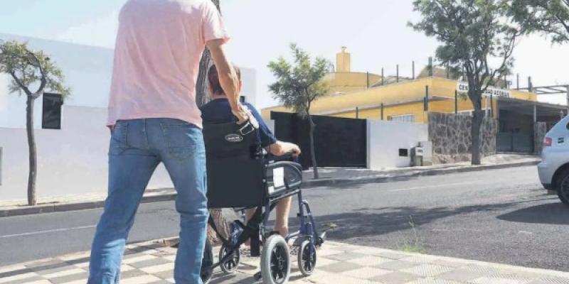 Un cuidador dando un paseo con una señora mayor.