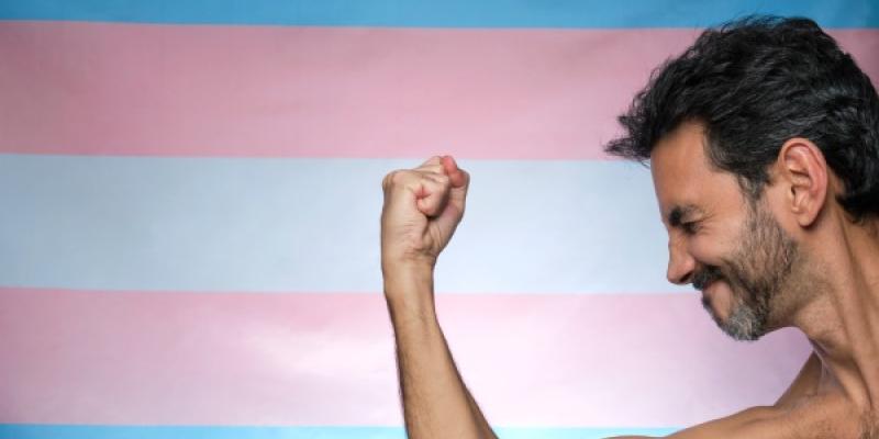 Chico con brazo musculoso sobre bandera transgénero