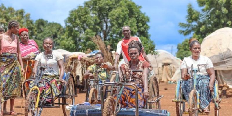 Mujeres en triciclos se abren paso por un campamento para personas desplazadas en Nigeria.