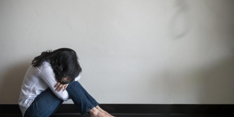 Chica encogida en el suelo y llorando