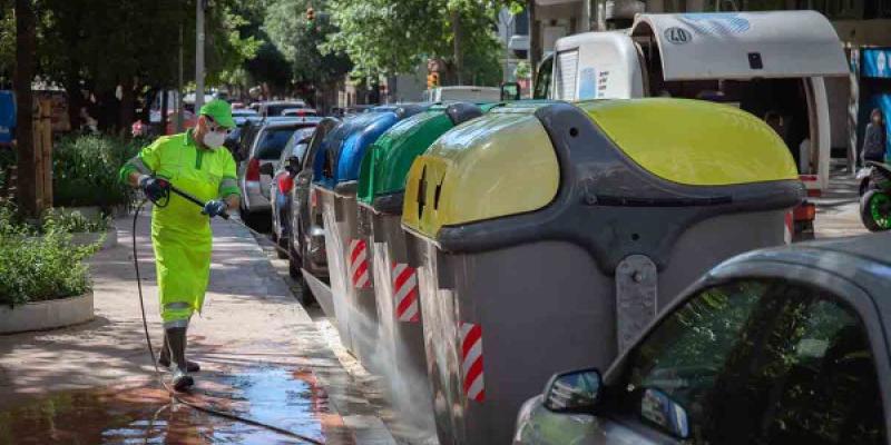 Operario de limpieza del servicio municipal desinfecta un contenedor amarillo de residuos