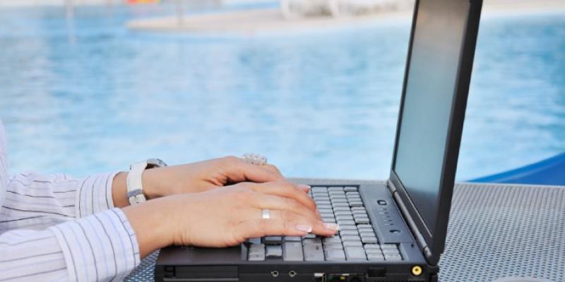 Una mujer trabaja con un ordenador portátil en una piscina