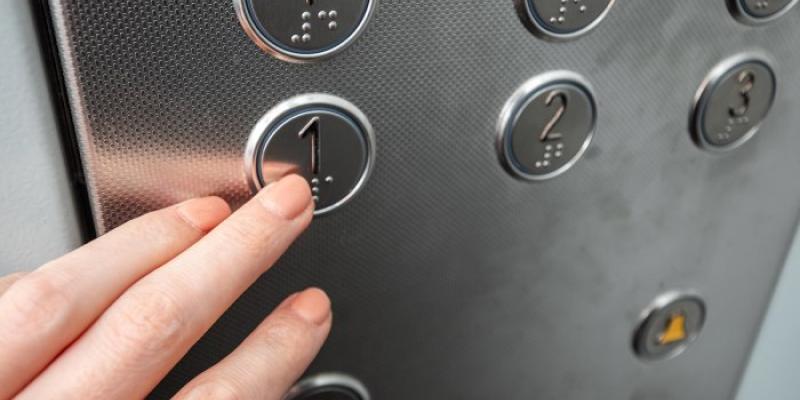 Una mujer pulsa un botón accesible en un ascensor 