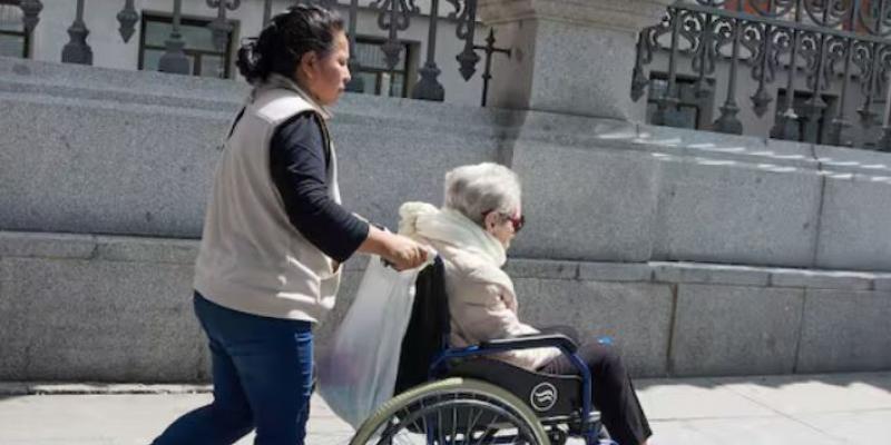 Mujer extranjera cuidado de una persona dependiente en silla de ruedas