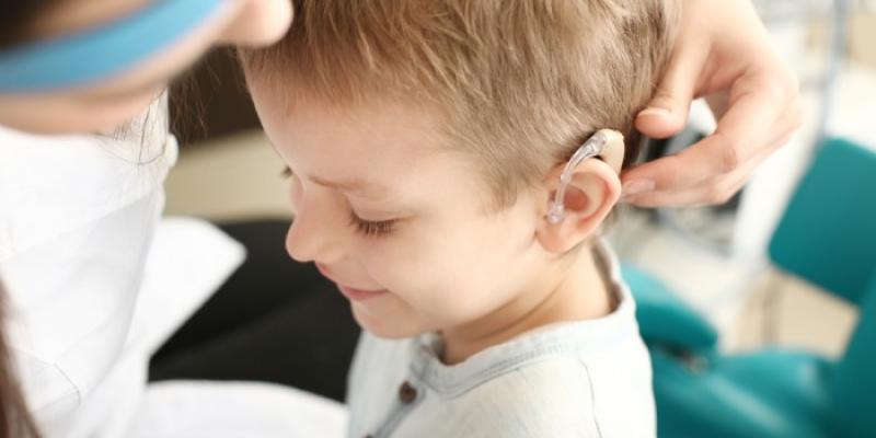 Una doctora coloca el audífono de un implante coclear a una niña 