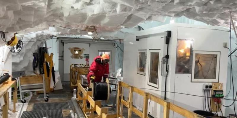 Un investigador baja un cable de fibra óptica dentro de un pozo para registrar señales del interior de la corriente de hielo en Groenlandia