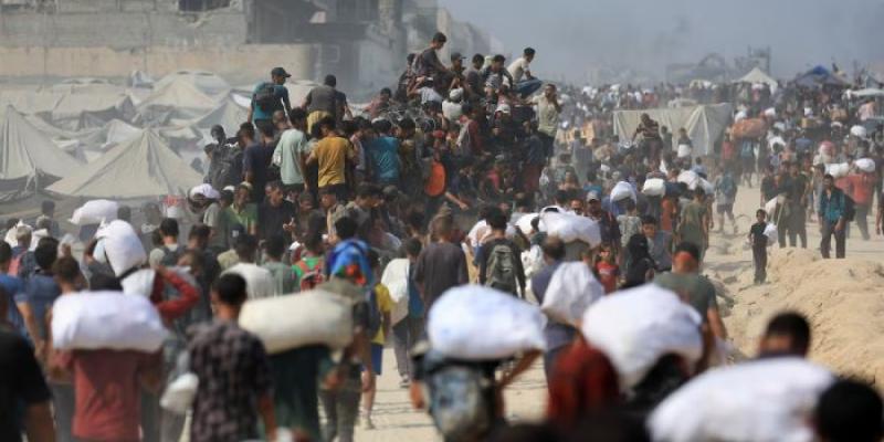 Cientos de ciudadanos palestinos transportan sacos con ayuda humanitaria 