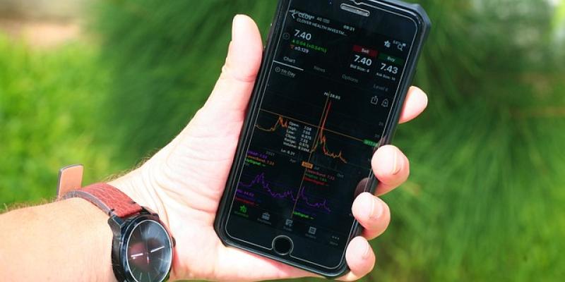 Mano de una persona con un teléfono móvil y una aplicación de la bolsa de valores, Ibex 35