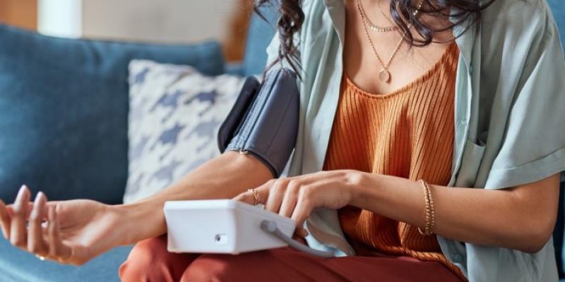 Una mujer sentada se toma la presión arterial 