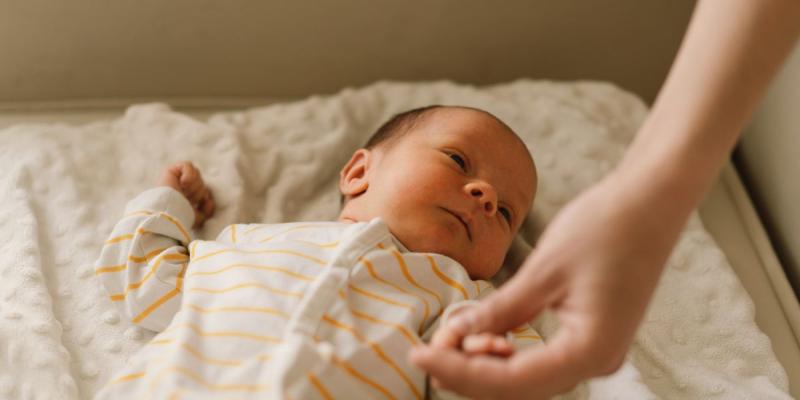 Un bebé agarra la mano de su madre 