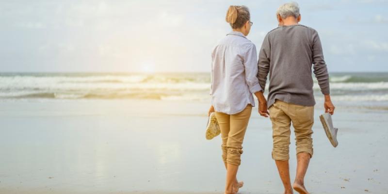 dos personas jubiladas paseando por la playa