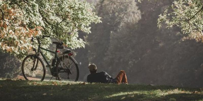 Señor descansando en el campo tumbado tras un paseo en bicicleta