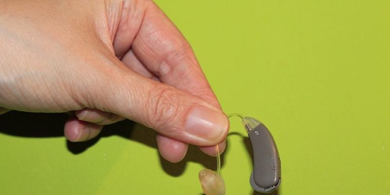 Mano de una persona con problemas de audición sujetando un audífono