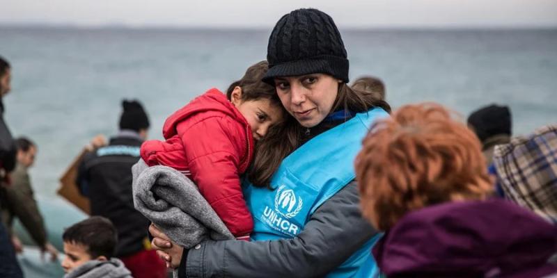 Una trabajadora de ACNUR sostiene en brazos a un niño refugiado envuelto en una manta. La embarcación en la que viajaba la criatura llegó a Lesvos, una isla griega.  