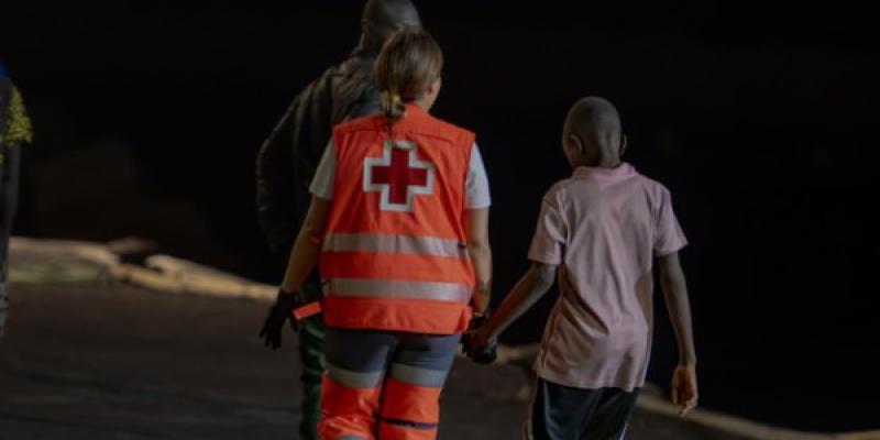 Un trabajador de la Cruz Roja atiende a menores migrantes llegados a Canarias