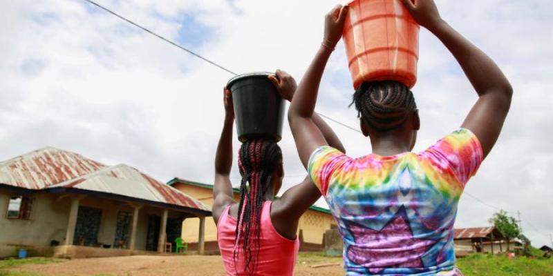 Dos jóvenes llevan agua sobre sus cabezas en Sierra Leona 