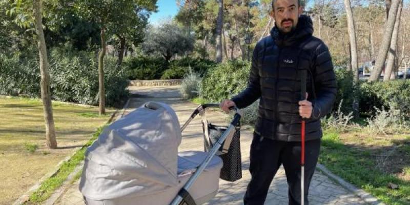 Javier con su bastón y el carrito de su hijo pequeño.
