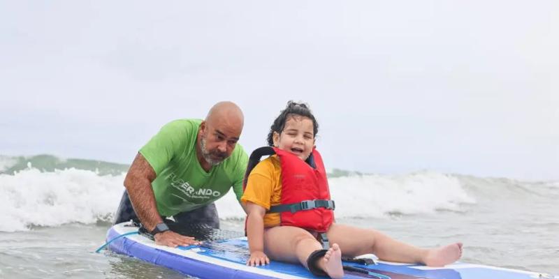 Víctor Alias apoya a una niña para hacer surf / Cedida por Superando