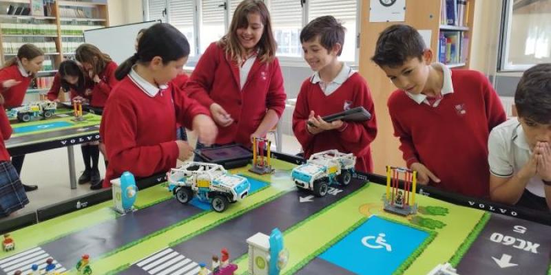 Foto de escolares trabajando en un proyecto en el que se ven vehículos, pasos de cebra y plazas de aparcamiento reservadas a personas con discapacidad