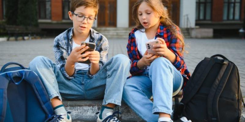 Niños sentados mirando el móvil