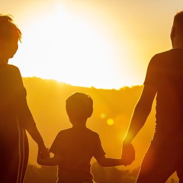 Familia de un padre, hijo y madre de espaldas en una puesta de sol
