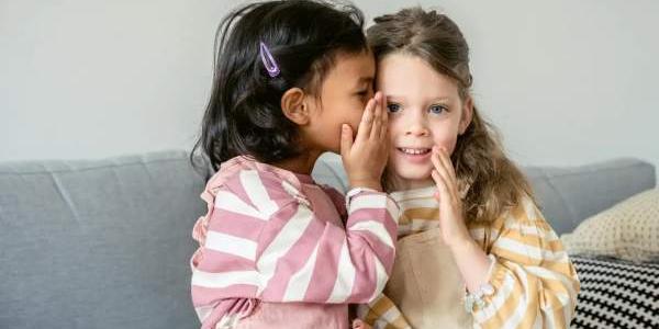 Dos niñas contándose un secreto al oído