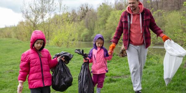 Un papá y sus hijas limpiando el medio ambiente del bosque.