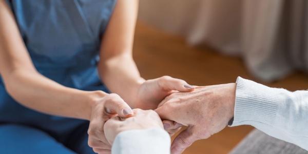 Manos de una persona dependiente y su cuidadora