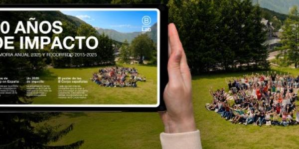 Imagen de una mano con una tablet haciendo una fotoa los miembros de una empresa en la naturaleza