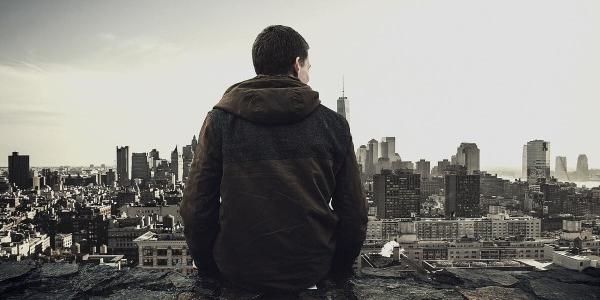 Chico de espaldas mirando una ciudad en blanco y negro