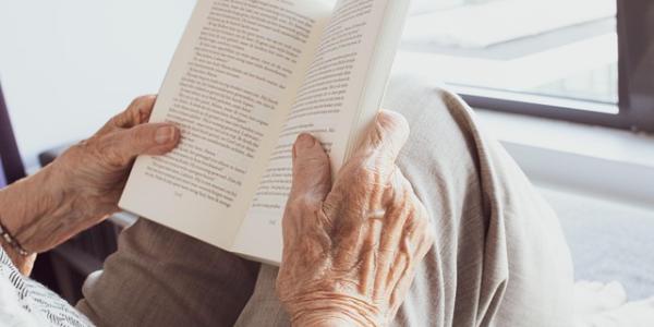Manos de una persona mayor leyendo un libro