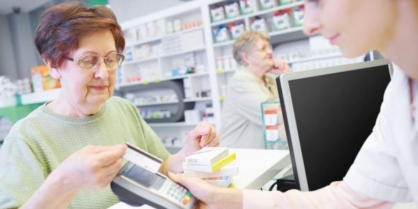 Mujer mayor pagando sus medicinas en la farmacia