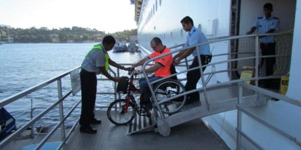Las tripulaciones de los barcos de crucero ayudabdo a un pasajero con movilidad reducida