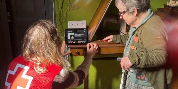 Una mujer mayor, acompañada de una voluntaria de Cruz Roja 