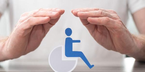 Manos de una persona abrazando el símbolo de alguien en silla de ruedas