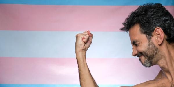 Chico con brazo musculoso sobre bandera transgénero