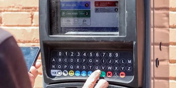Una persona utiliza un parquímetro, en Madrid.