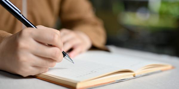 Manos de una persona escribiendo un libro